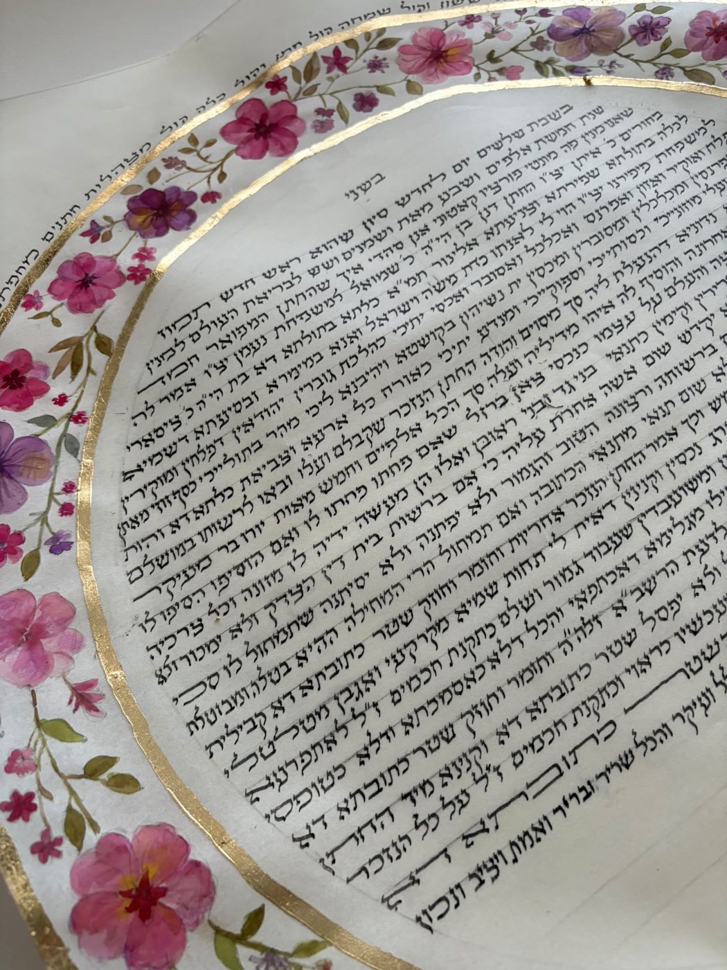 Il dettaglio avvicina le corolle rosa e viola alla trama serrata della scrittura, mostrando come il sottile anello dorato separi con precisione i due registri.