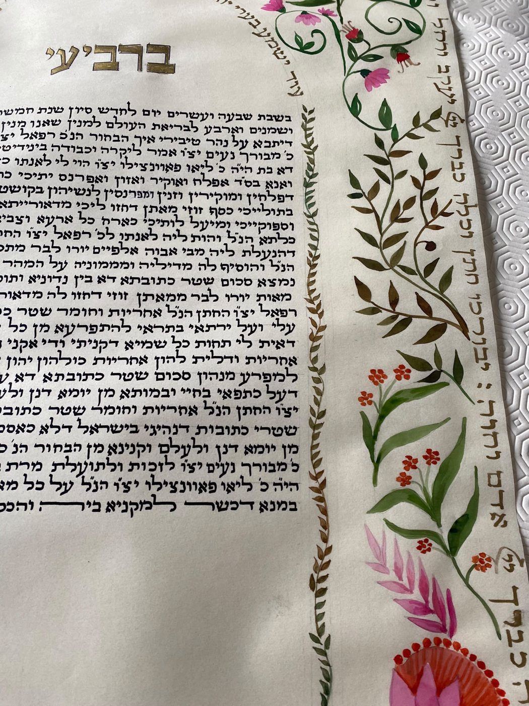 La cornice interna mostra il suo disegno minuto di foglioline, mentre all’esterno le grandi corolle rosa e i rami scuri introducono un contrasto più vigoroso.