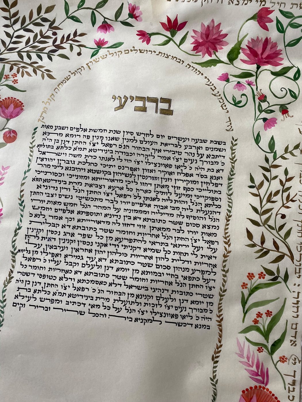 Un’altra veduta dell’opera evidenzia la forza del fregio superiore: ampie foglie brune e fiori porpora accompagnano l’arco calligrafico sopra l’intestazione dorata.