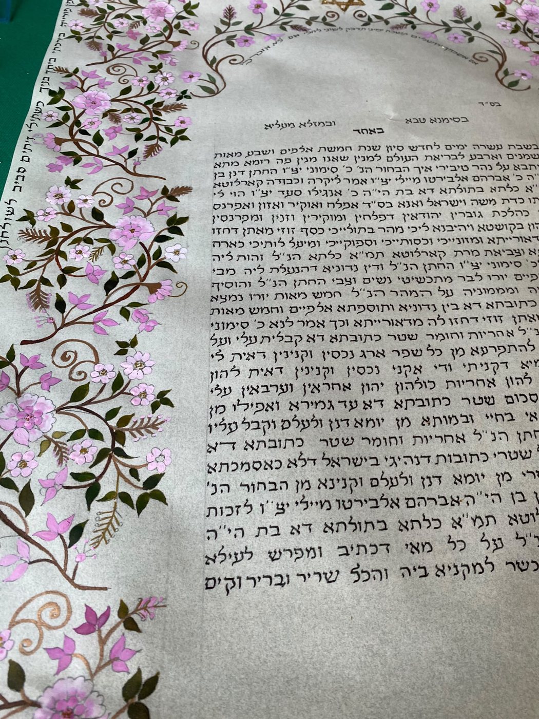 Sul lato sinistro, i tralci bruni e i fiori lilla si stagliano sul fondo chiaro; le ramificazioni minute introducono un movimento leggero accanto alla calligrafia.